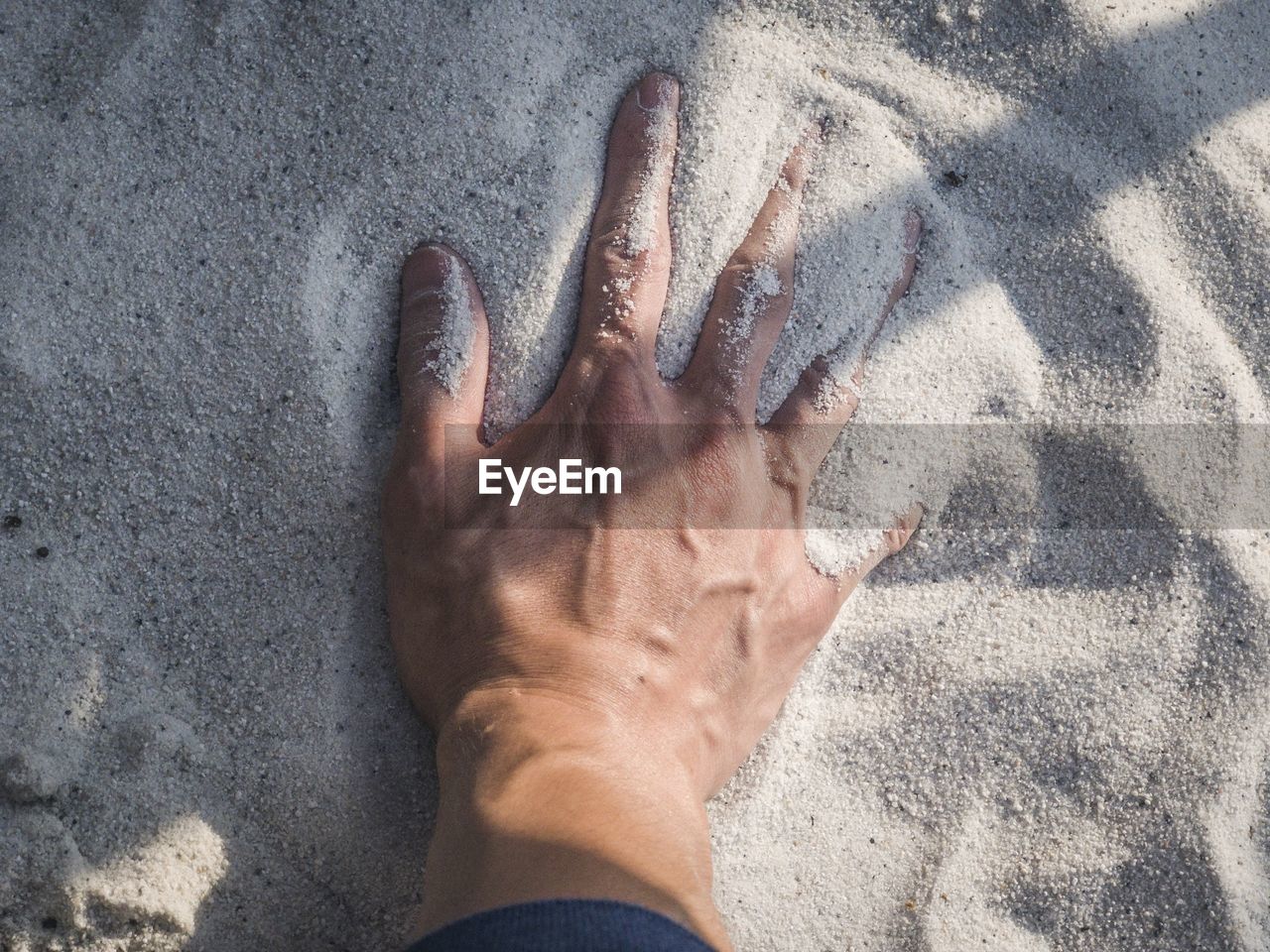 High angle view of cropped hand in sand