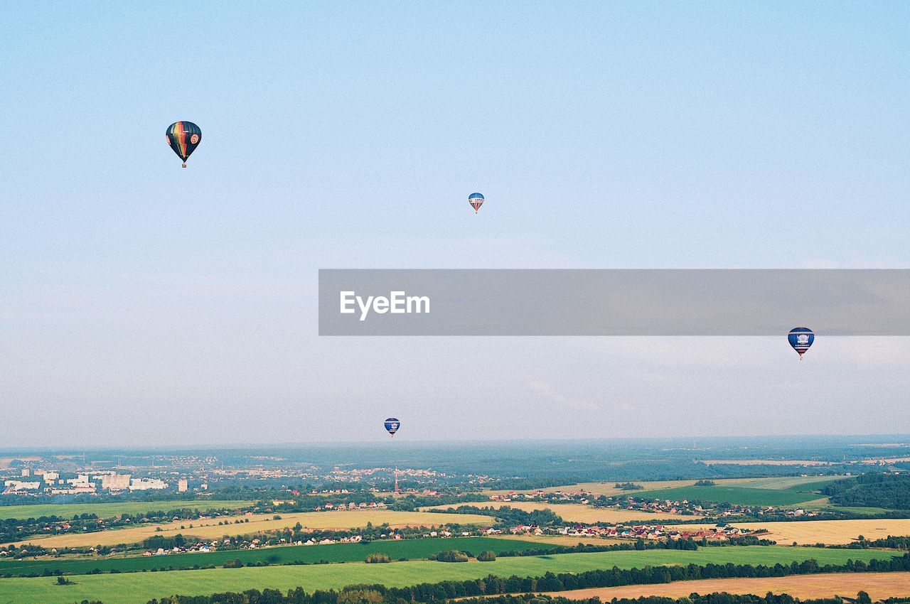 Hot air balloons flying over landscape against sky