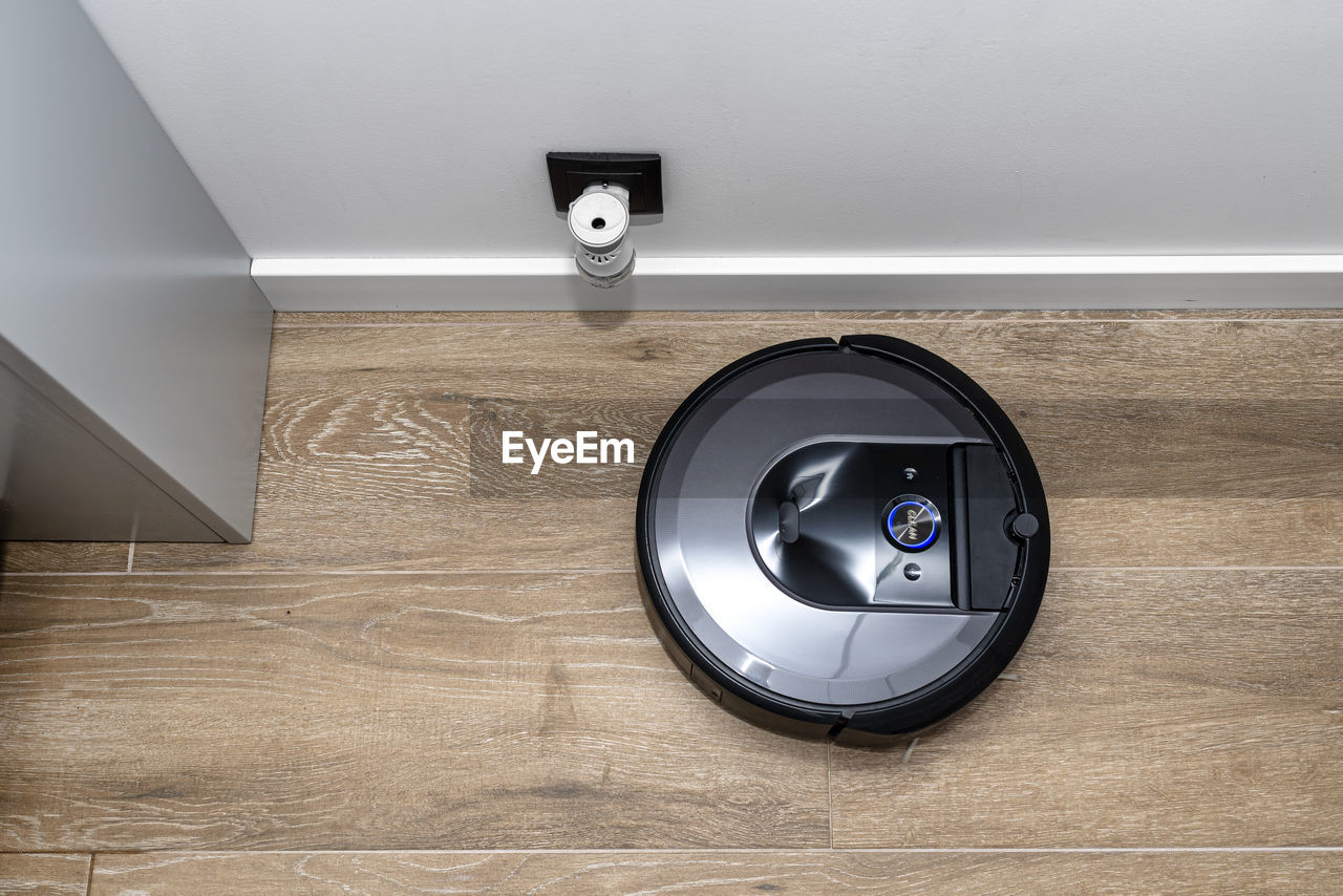 A modern robotic vacuum cleaner cleans the ceramic tiles in the bathroom next to the electric socket