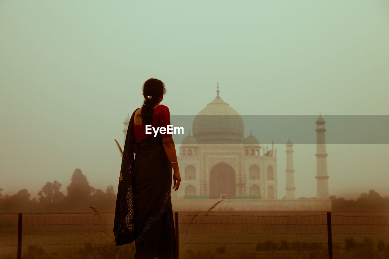 Rear view of woman standing against taj mahal