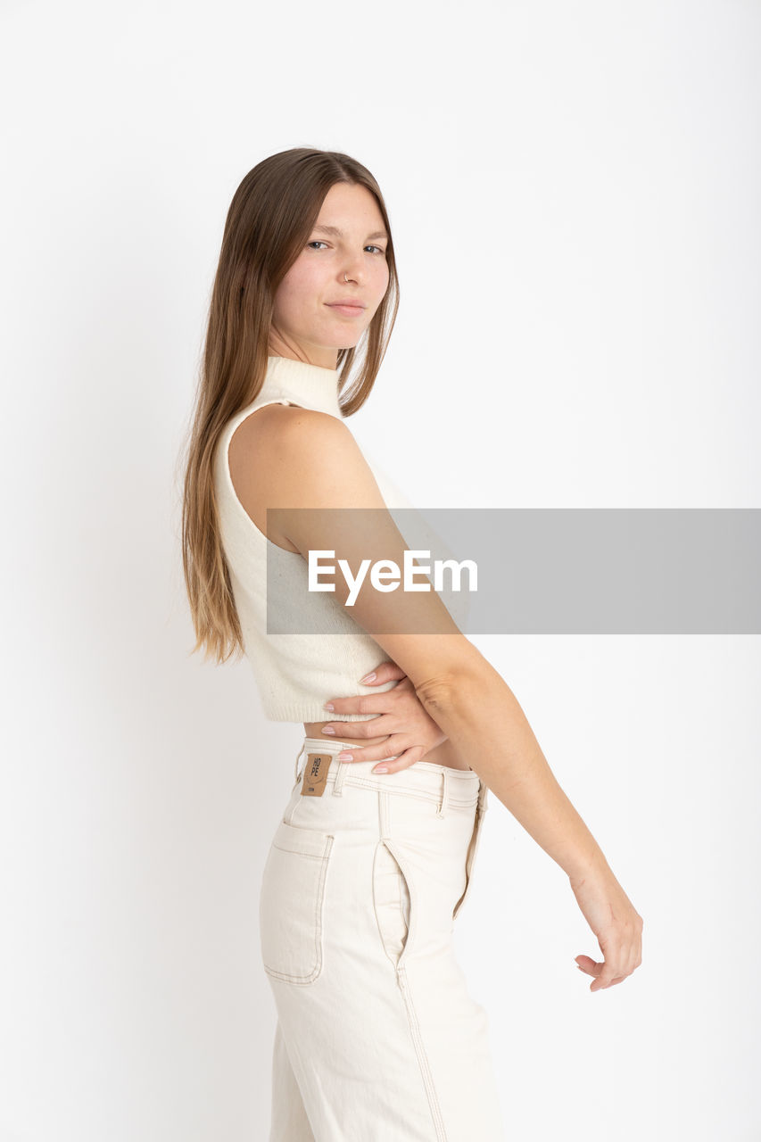Portrait of young woman standing against white background