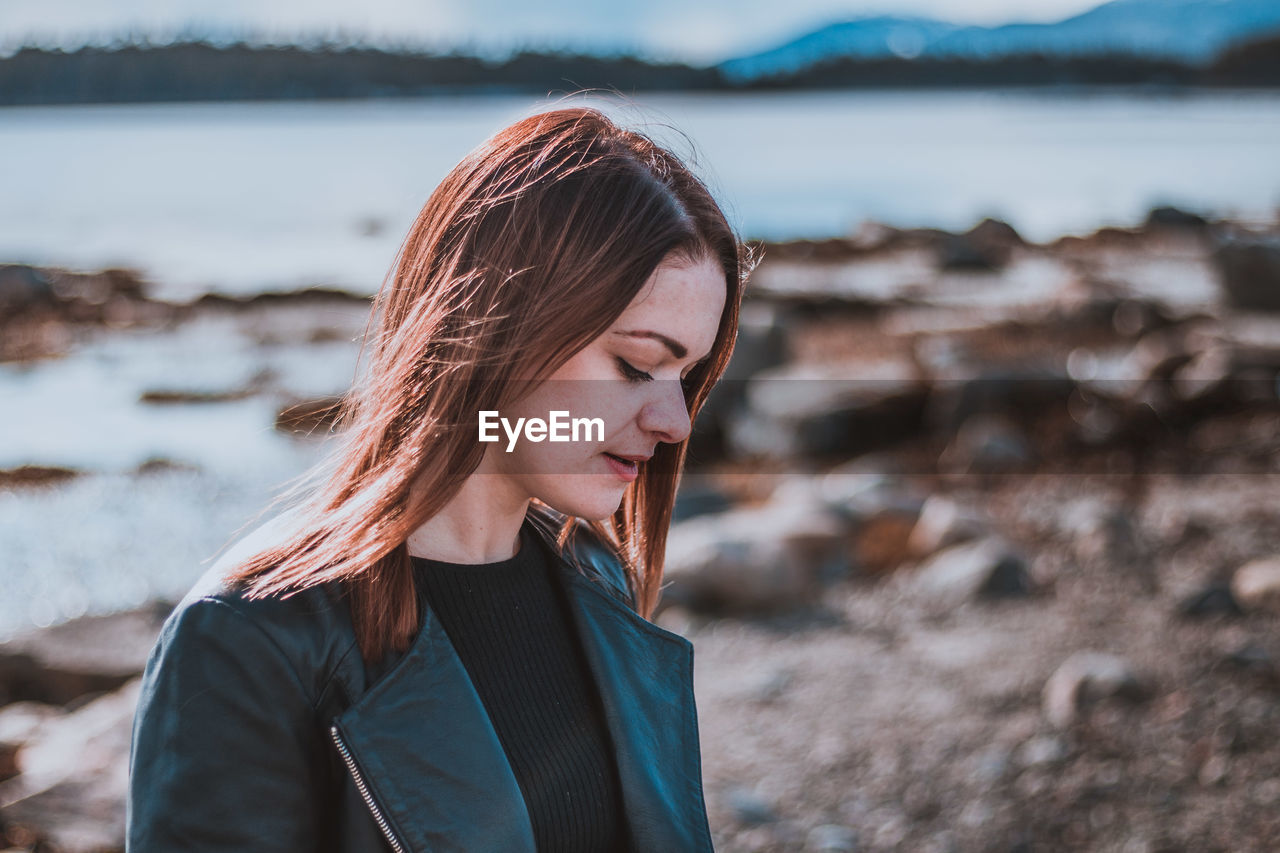 BEAUTIFUL YOUNG WOMAN LOOKING AT SEA SHORE