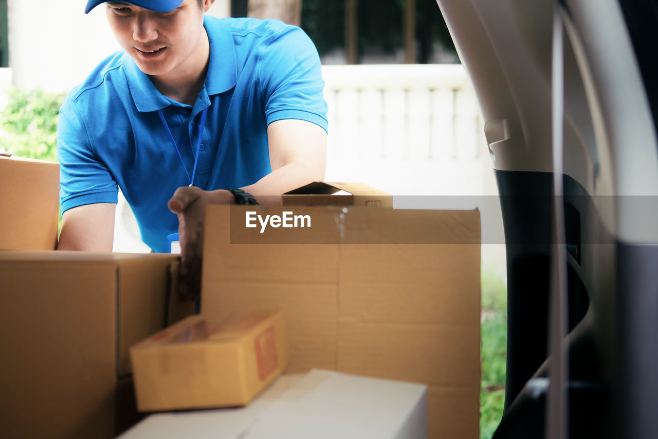 Delivery man removing packages from car