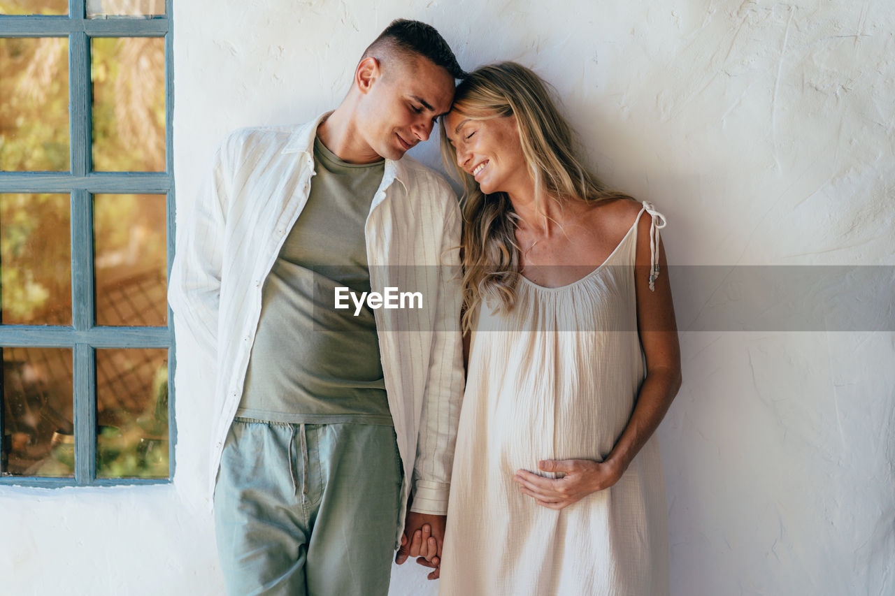 Couple in love standing near the wall. a pregnant woman holds her husband's hand.