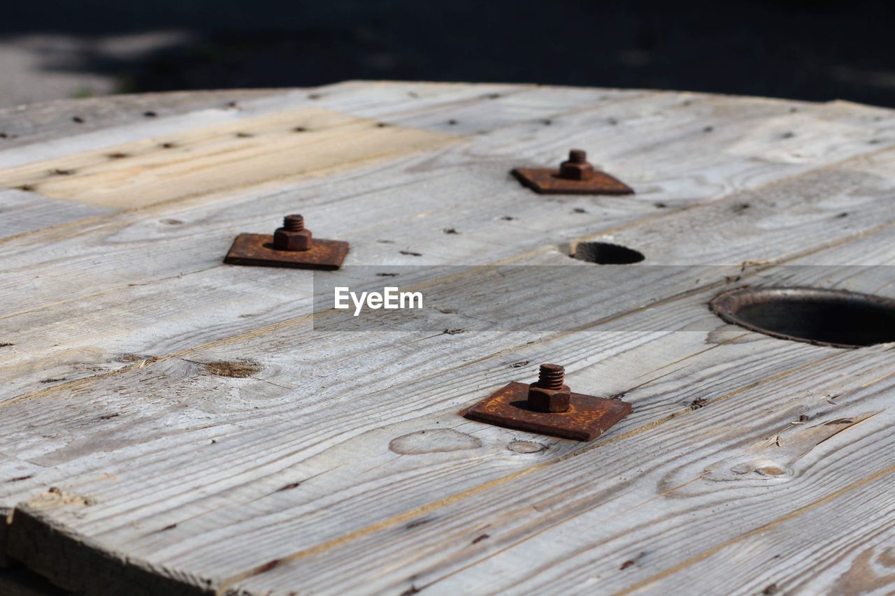 High angle view of rusty metallic bolts on wood