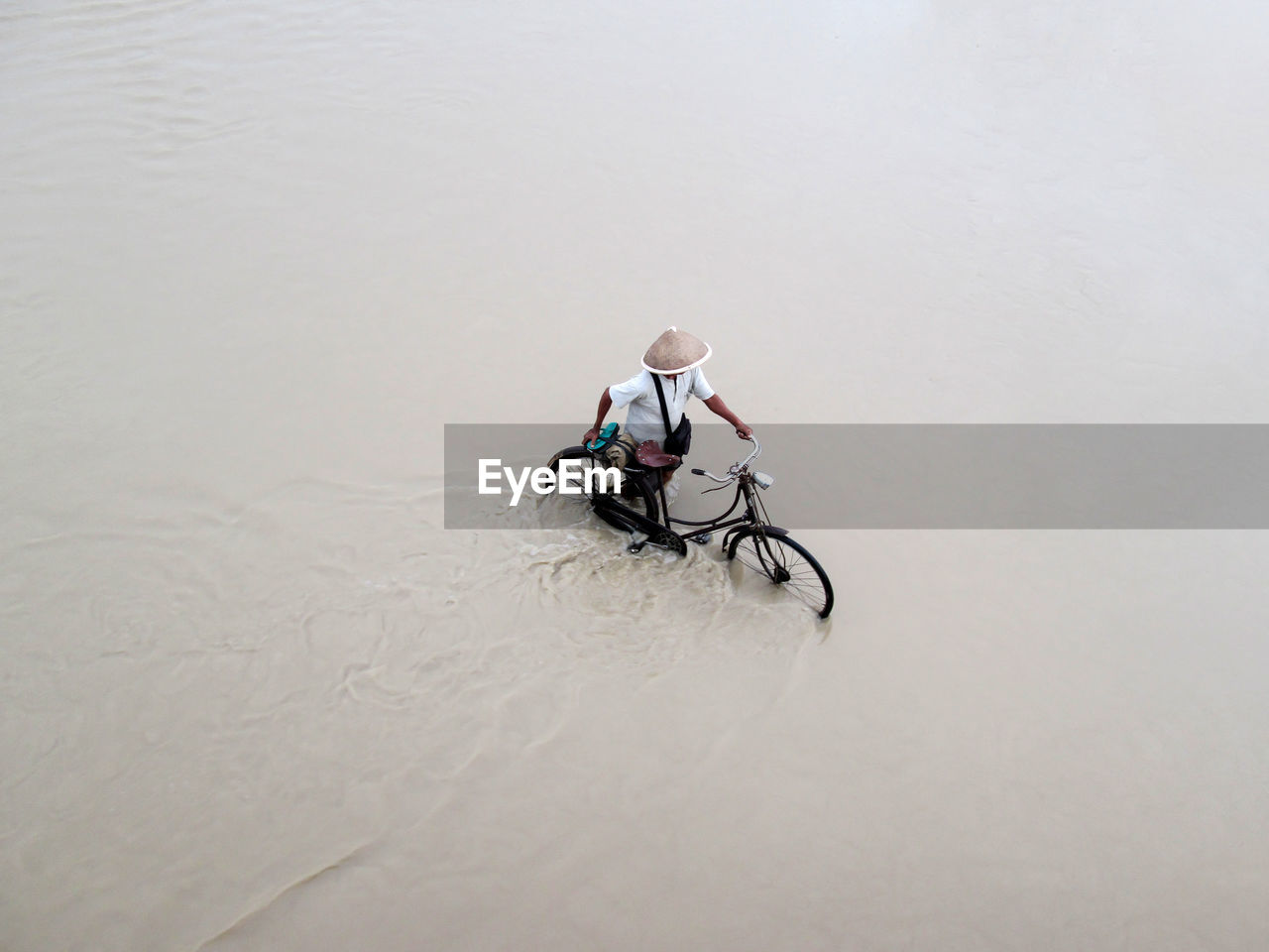 High angle view of man walking with bicycle in water