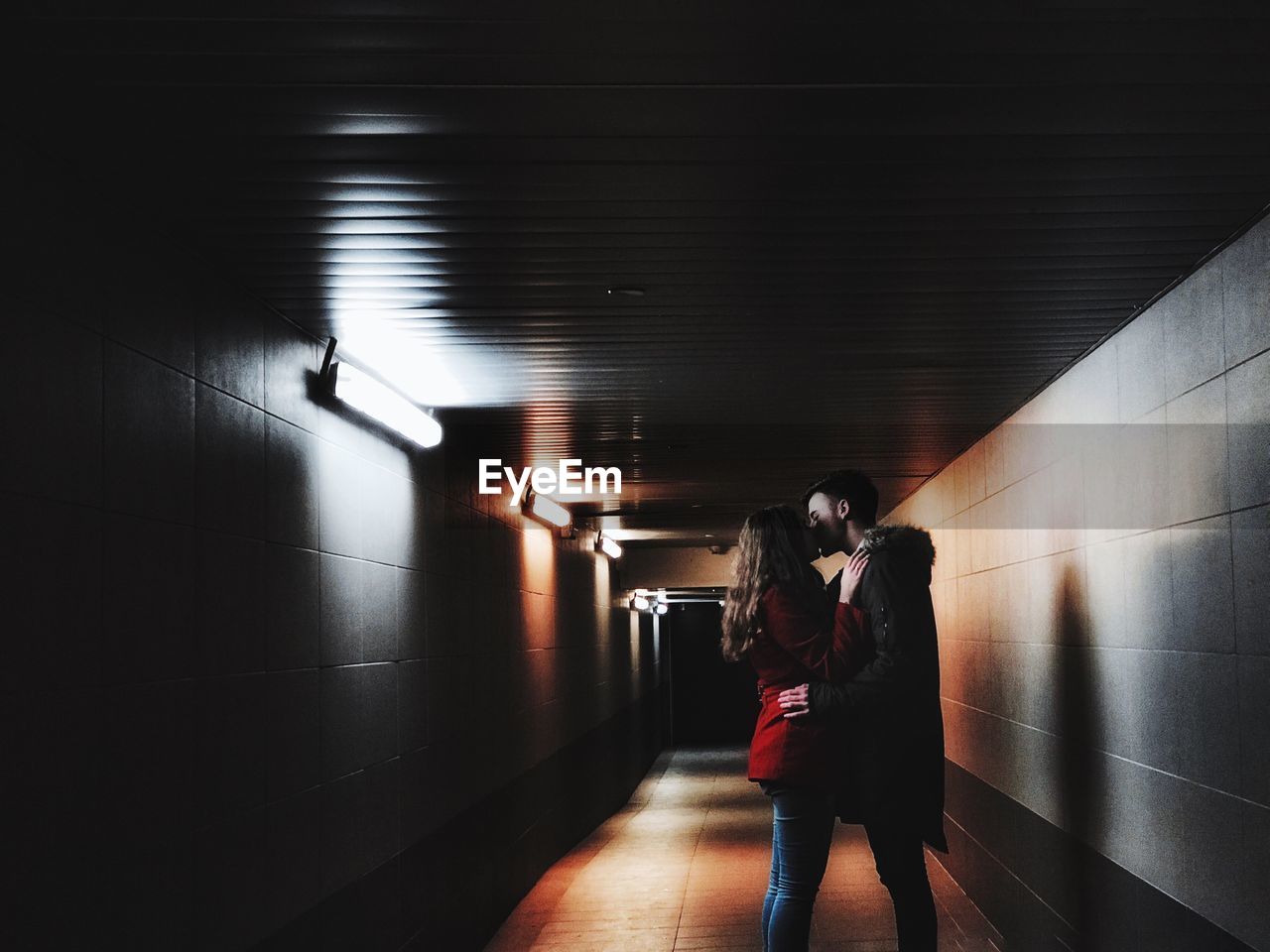 Side view of couple standing in illuminated corridor