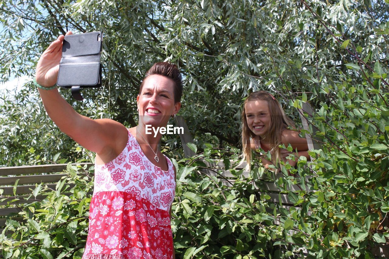 Happy mother and daughter taking selfie through mobile phone at park