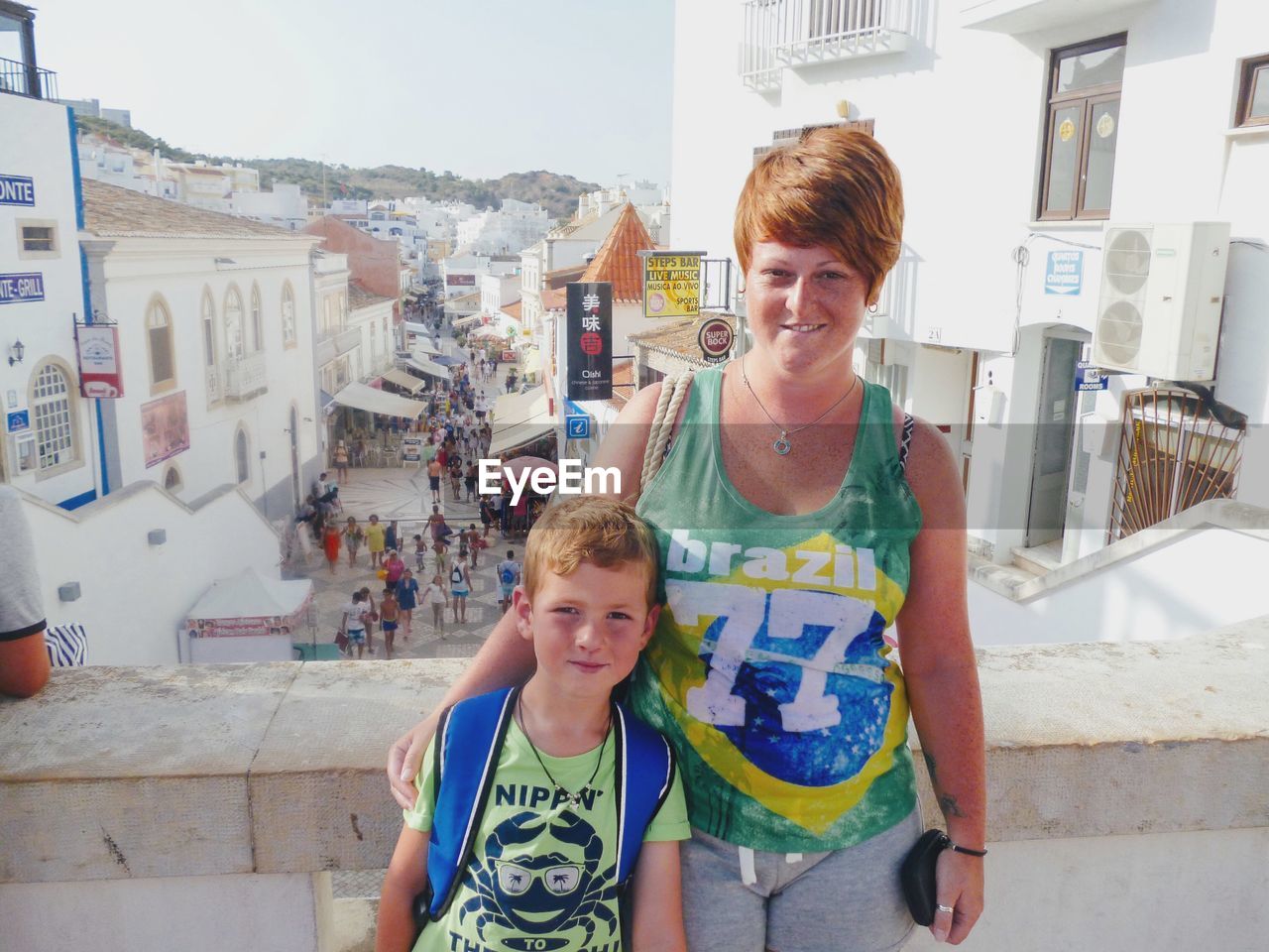 Portrait of smiling woman with boy standing against buildings