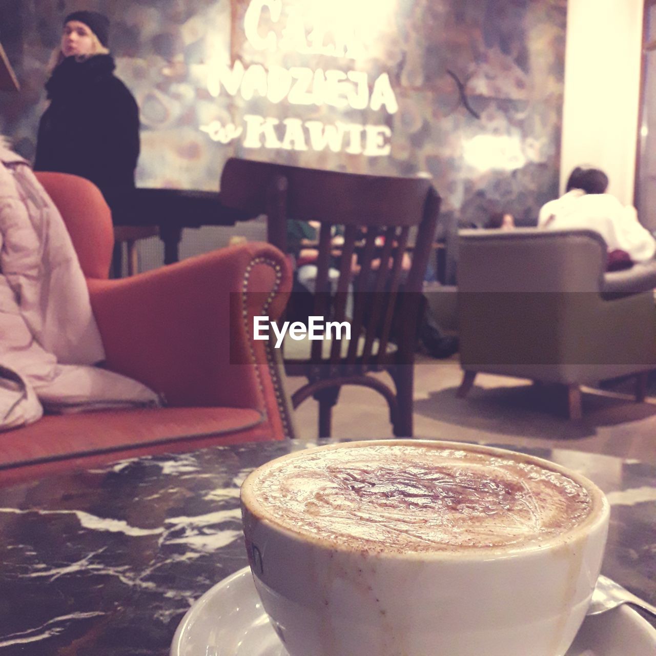 food and drink, drink, coffee, refreshment, cafe, table, coffeehouse, coffee cup, cup, mug, hot drink, indoors, restaurant, business, relaxation, adult, seat, chair, food, furniture, cappuccino, sitting, coffee shop, lifestyles, women, frothy drink, focus on foreground