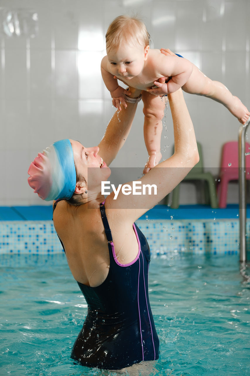 Early age swimming in pool. baby boy trained to swim in water. happy child  active parent