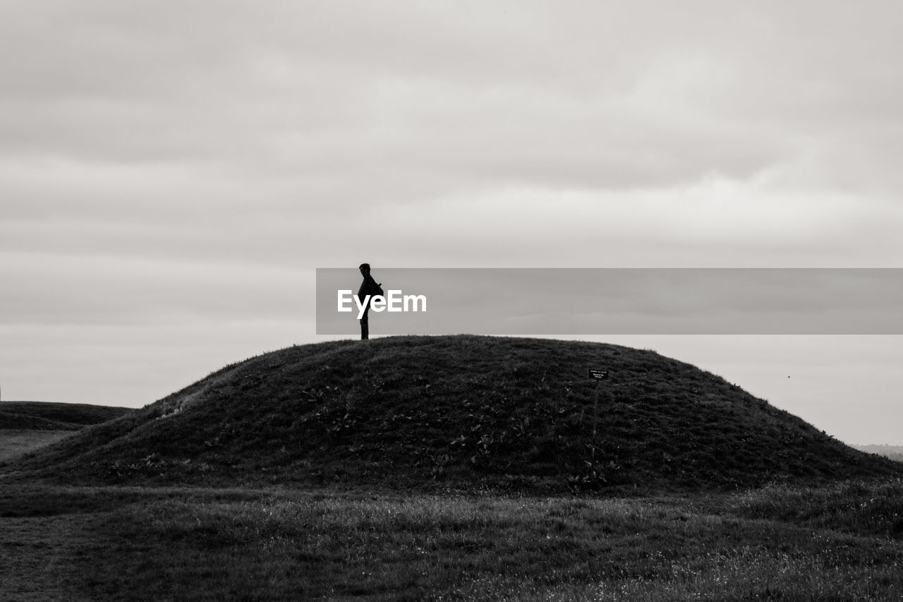 Man standing on hill against sky