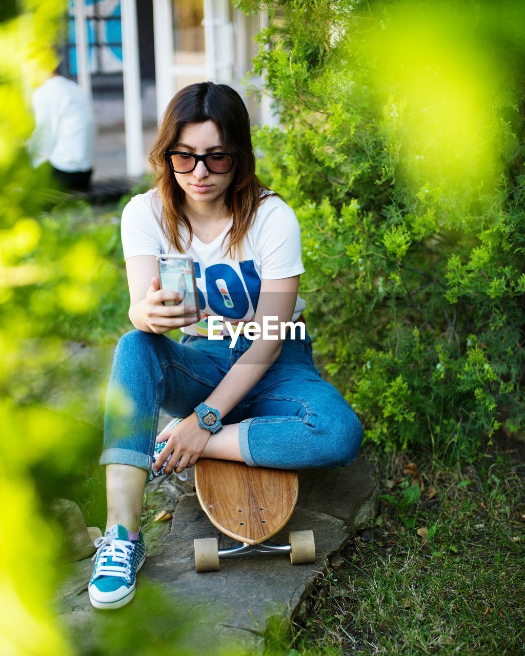 PORTRAIT OF A SMILING YOUNG WOMAN SITTING ON WALL