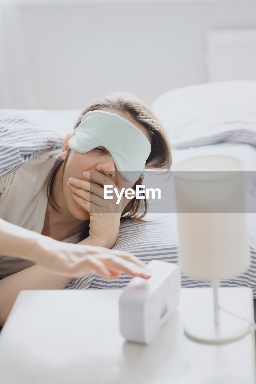 young woman using mobile phone while sitting on bed