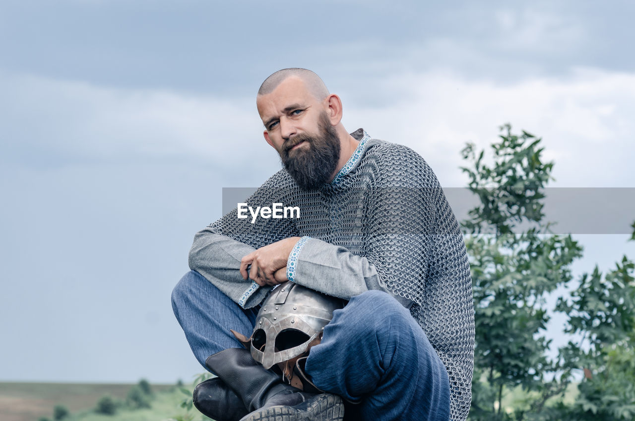 Side view of man in medieval viking clothing. metal helmet and chain mail. blurred background.