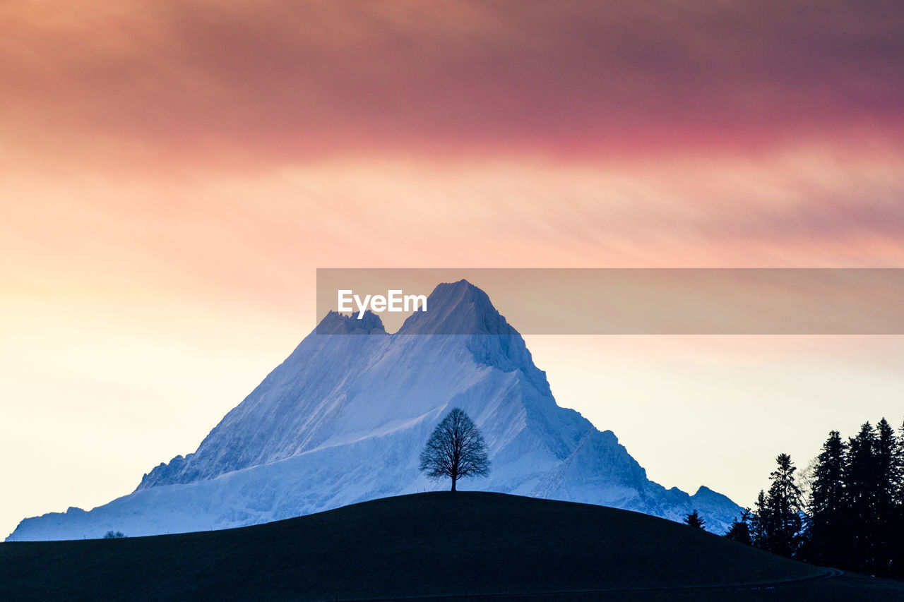 SNOWCAPPED MOUNTAINS AGAINST SKY DURING SUNSET