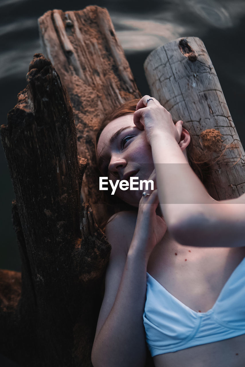 High angle view of woman lying on log over lake