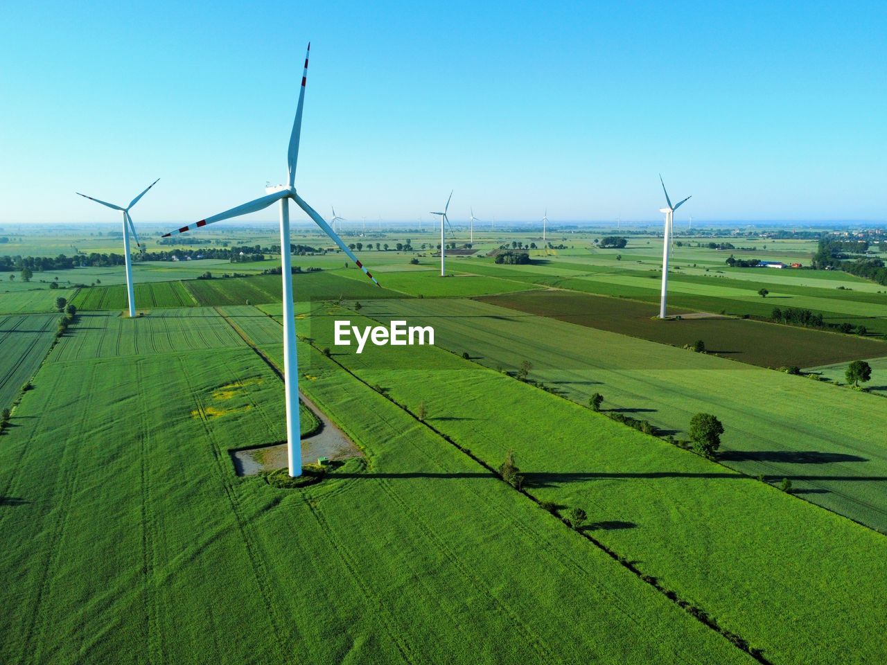 Windmills on field against clear blue sky