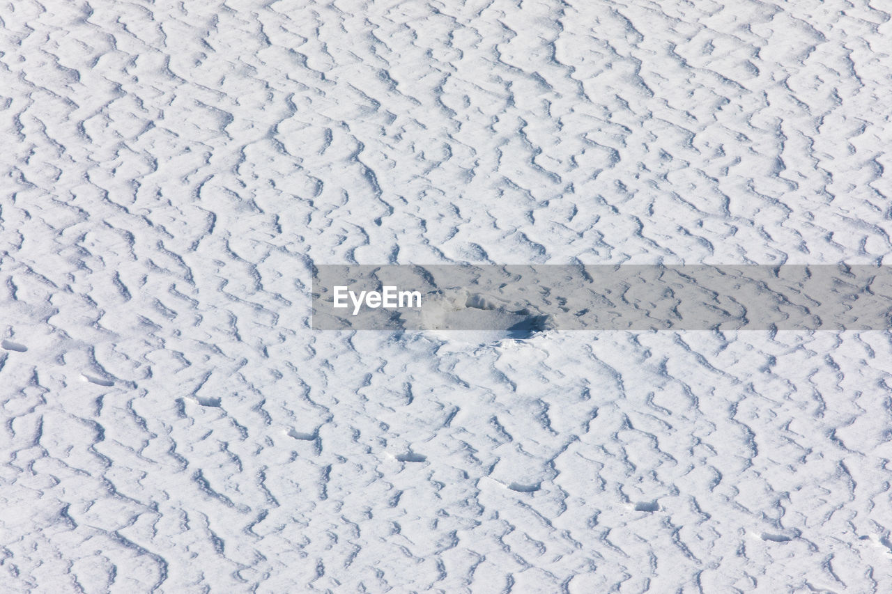 HIGH ANGLE VIEW OF SNOW ON COBBLESTONE FIELD