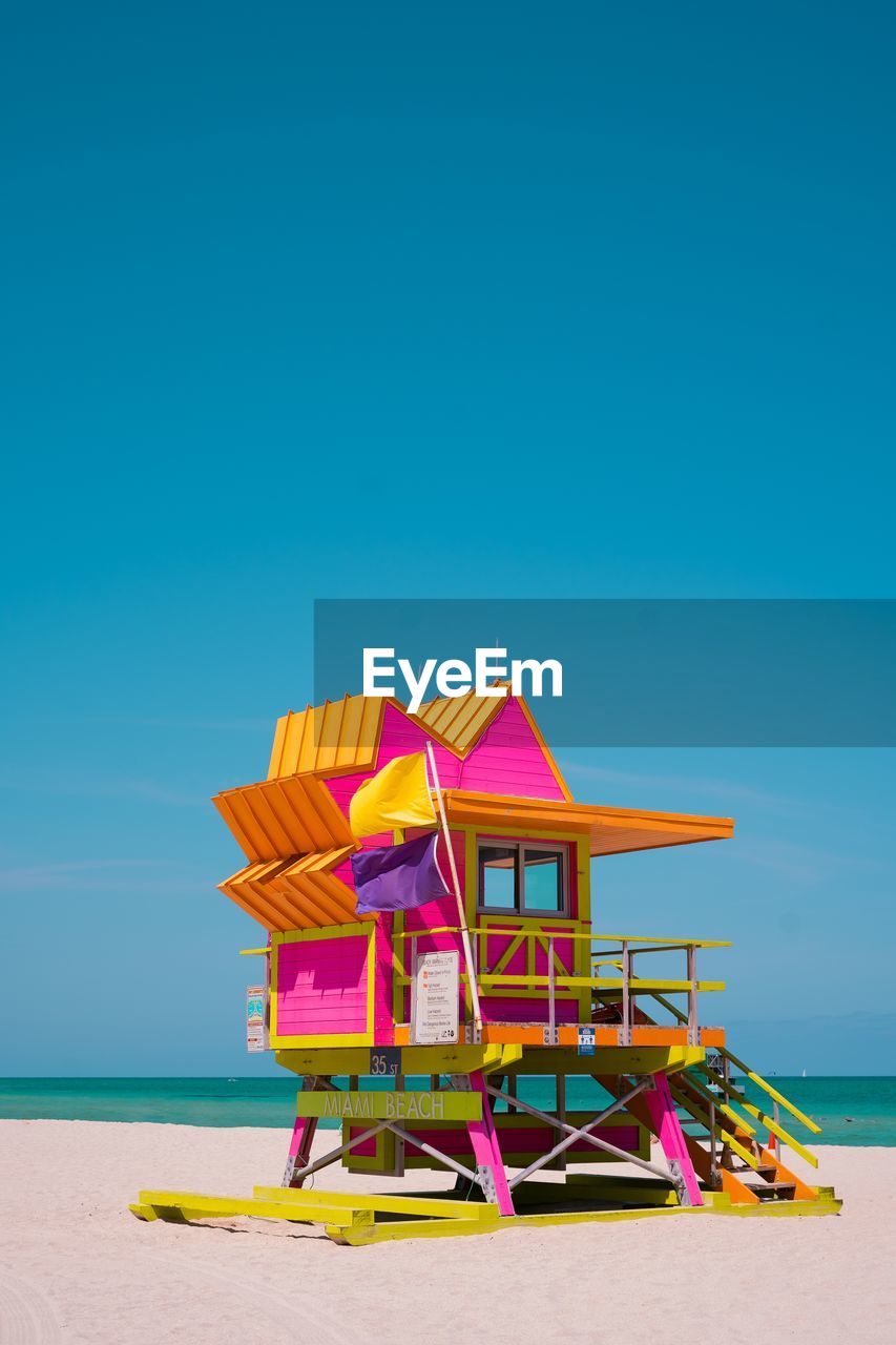 Colorful lifeguard hut on beach against clear blue sky