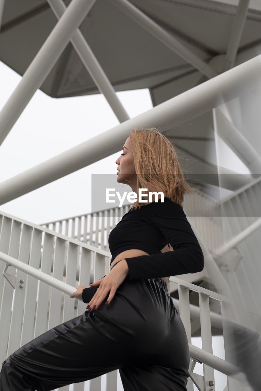 Side view of young woman standing on railing