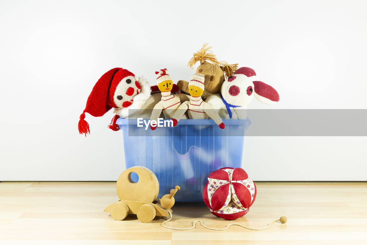 Cute and funny vintage children toys in a blue plastic box in front of a white wall. 