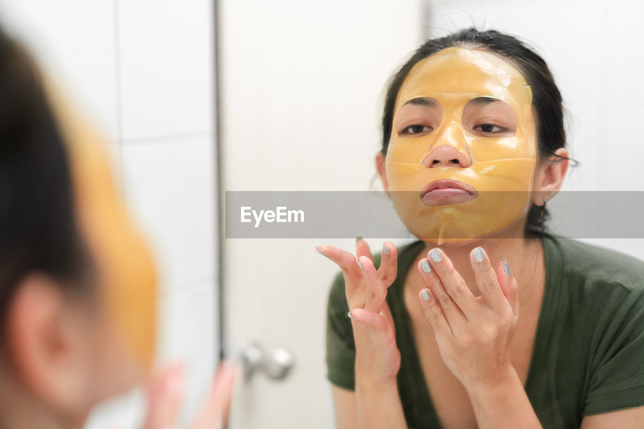 Close-up of woman applying facial mask