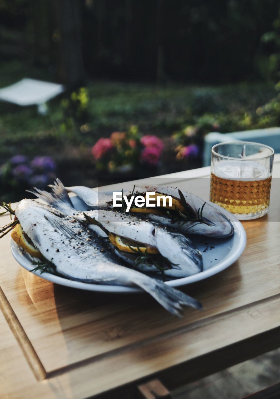Delicious fishes filled with lemin and rosemary next to a glass of beer