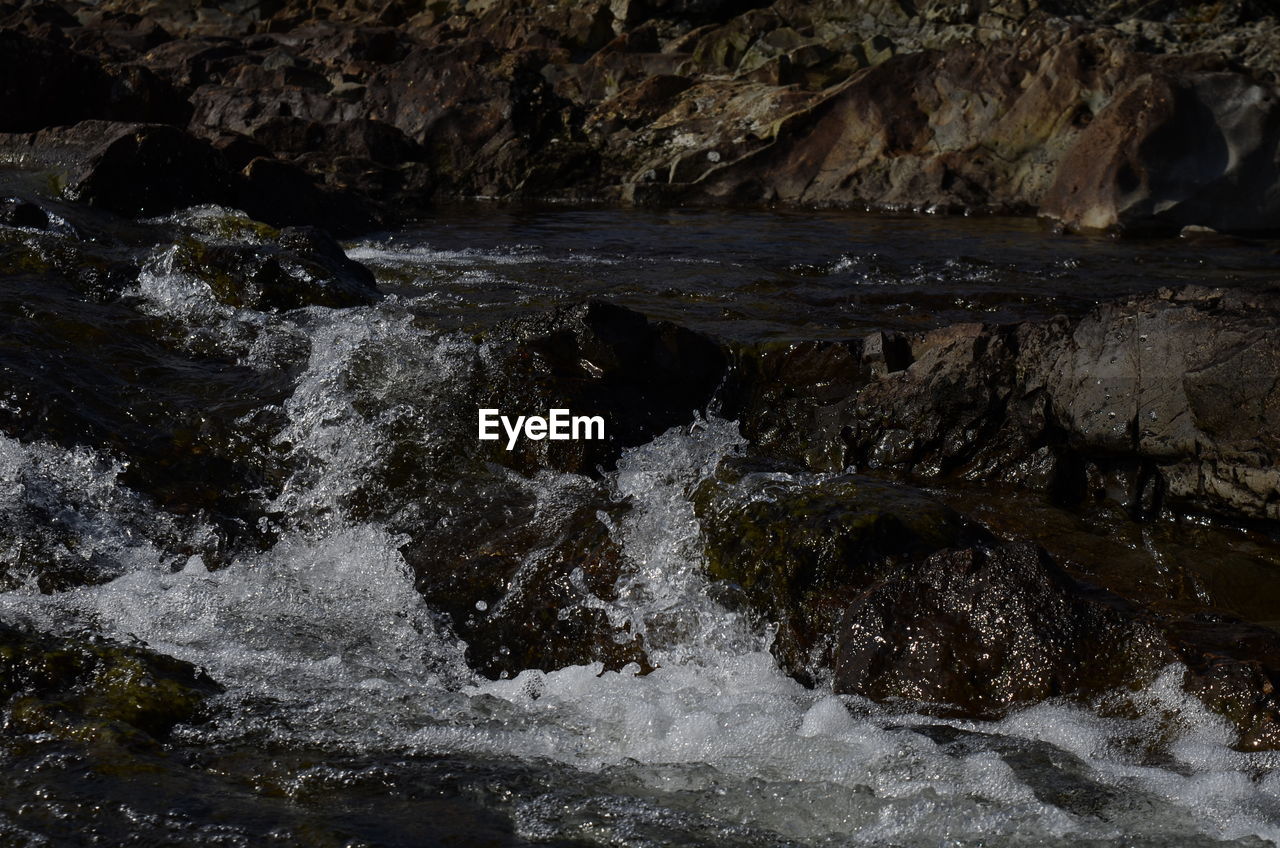 WATER FLOWING OVER ROCKS