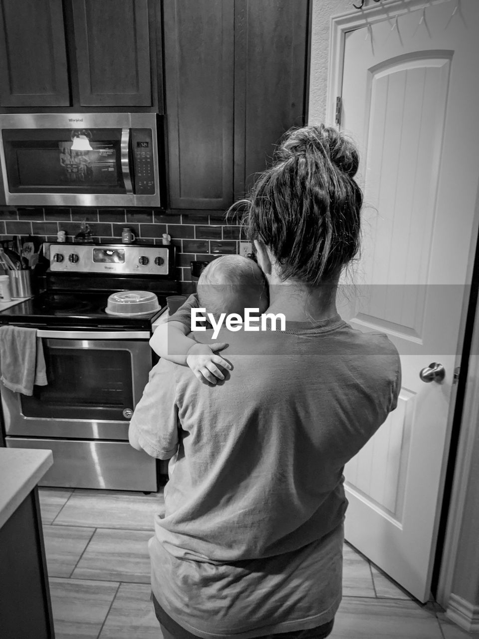 Rear view of woman with baby standing in kitchen