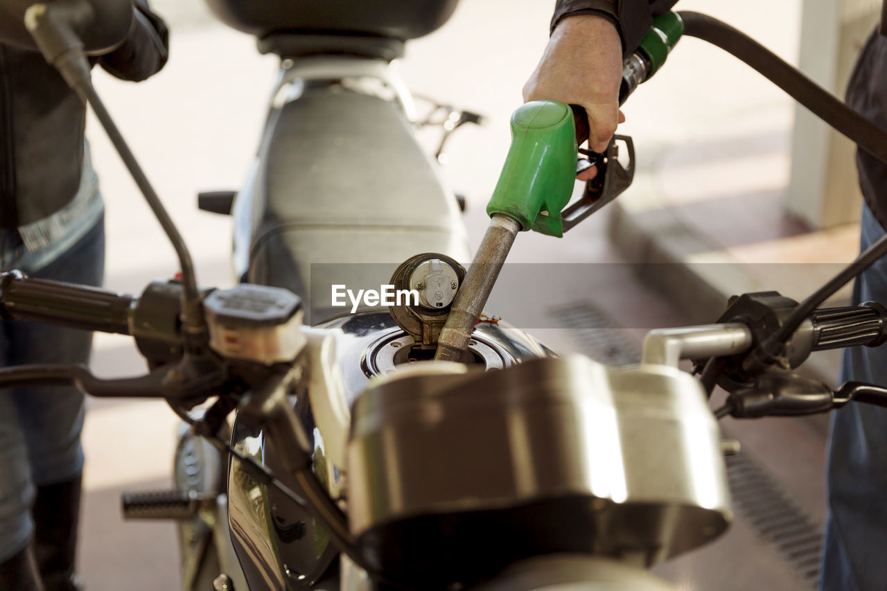 Cropped image of senior bikers refueling motorcycle at gas station