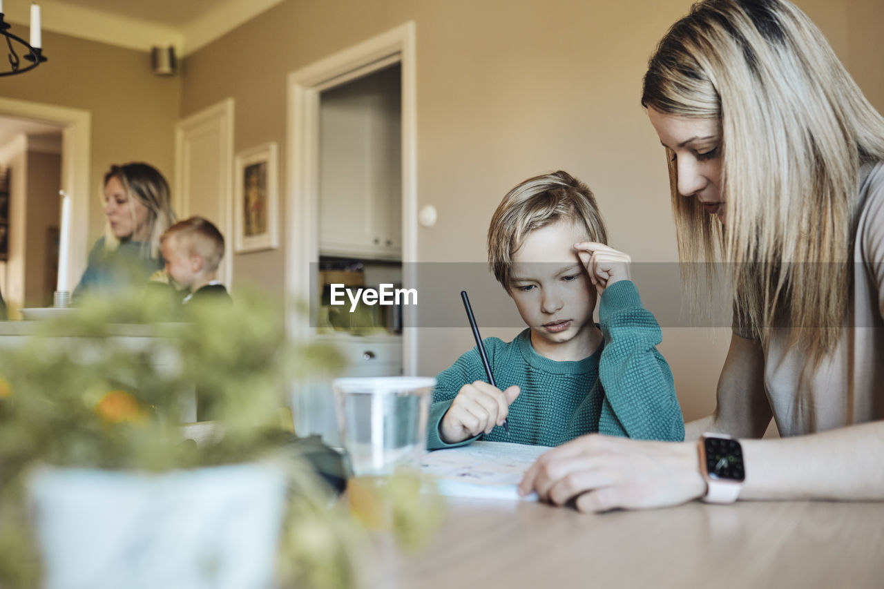 Blond woman assisting son with homework at home