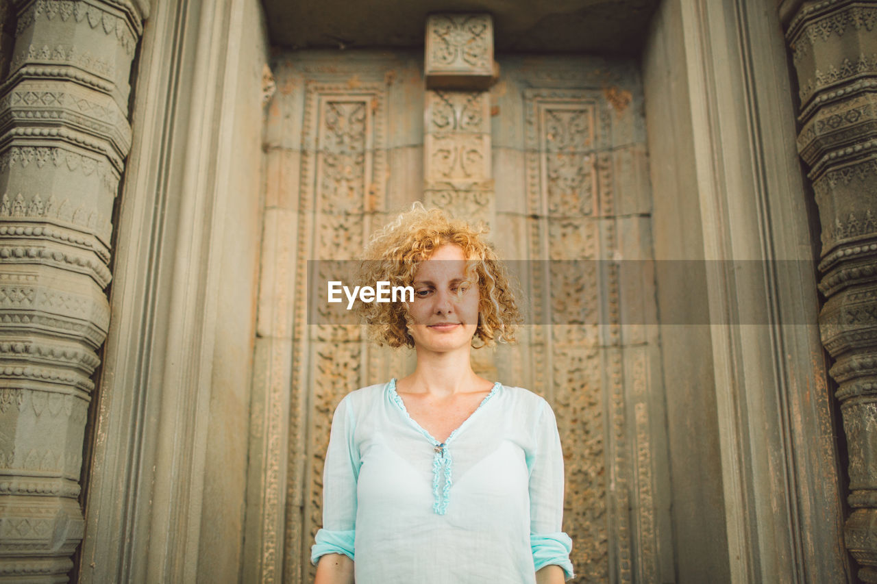 Smiling mid adult woman standing outside ankor wat temple