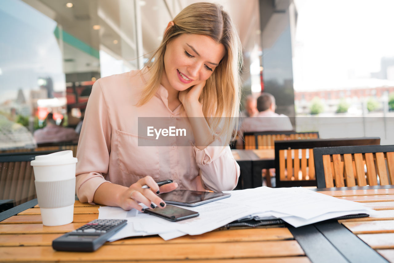 YOUNG WOMAN USING MOBILE PHONE IN CAFE