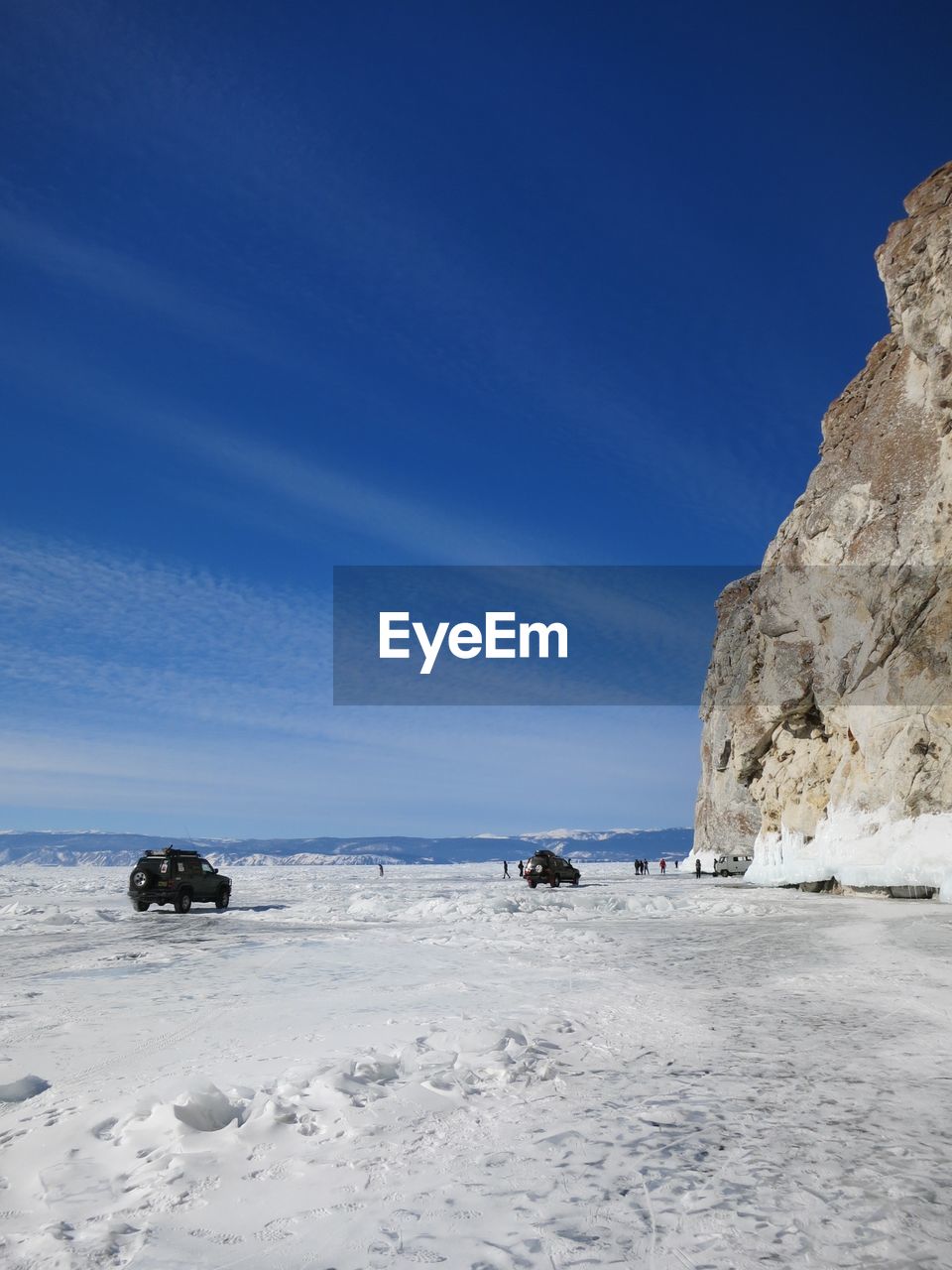 Scenic view of snowcapped mountains against blue sky on frozen lake