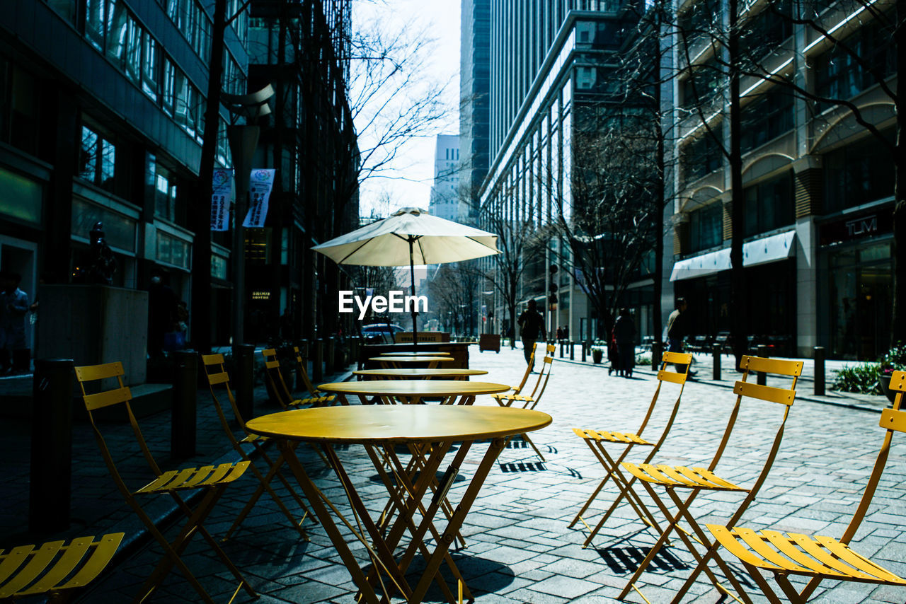 Empty chairs and tables at cafe in city