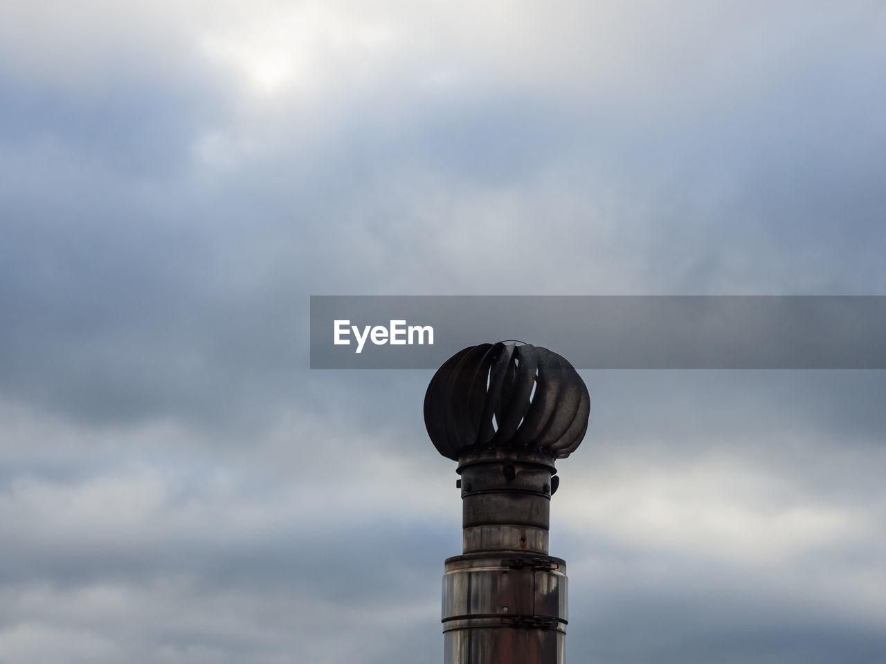 Smoke stack against cloudy sky