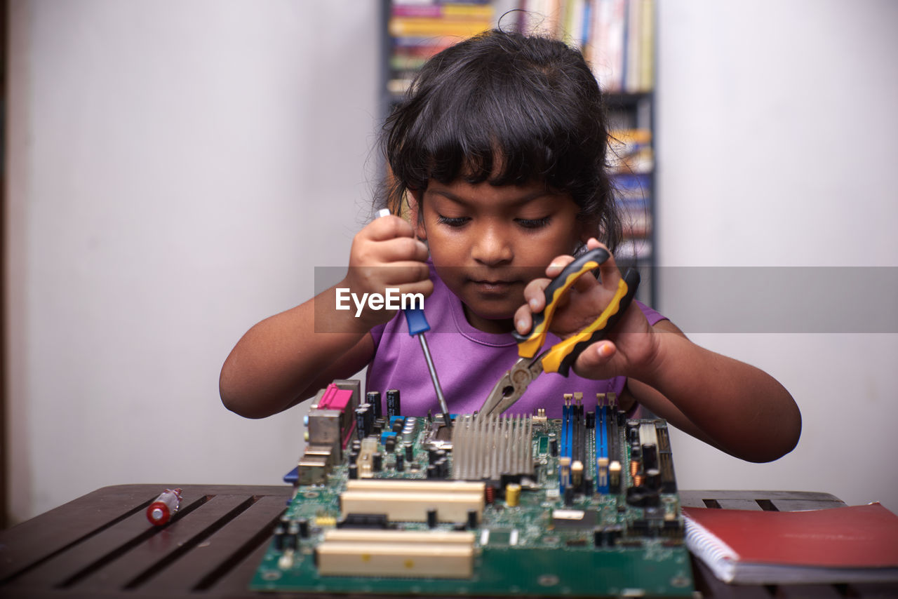 Little girl playing with motherboard computer at home