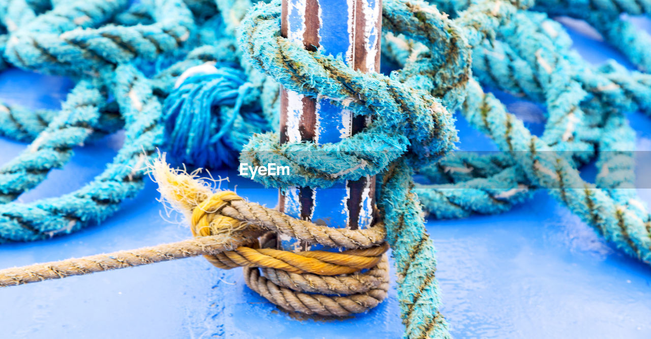 HIGH ANGLE VIEW OF ROPE TIED TO FISHING BOAT AT HARBOR