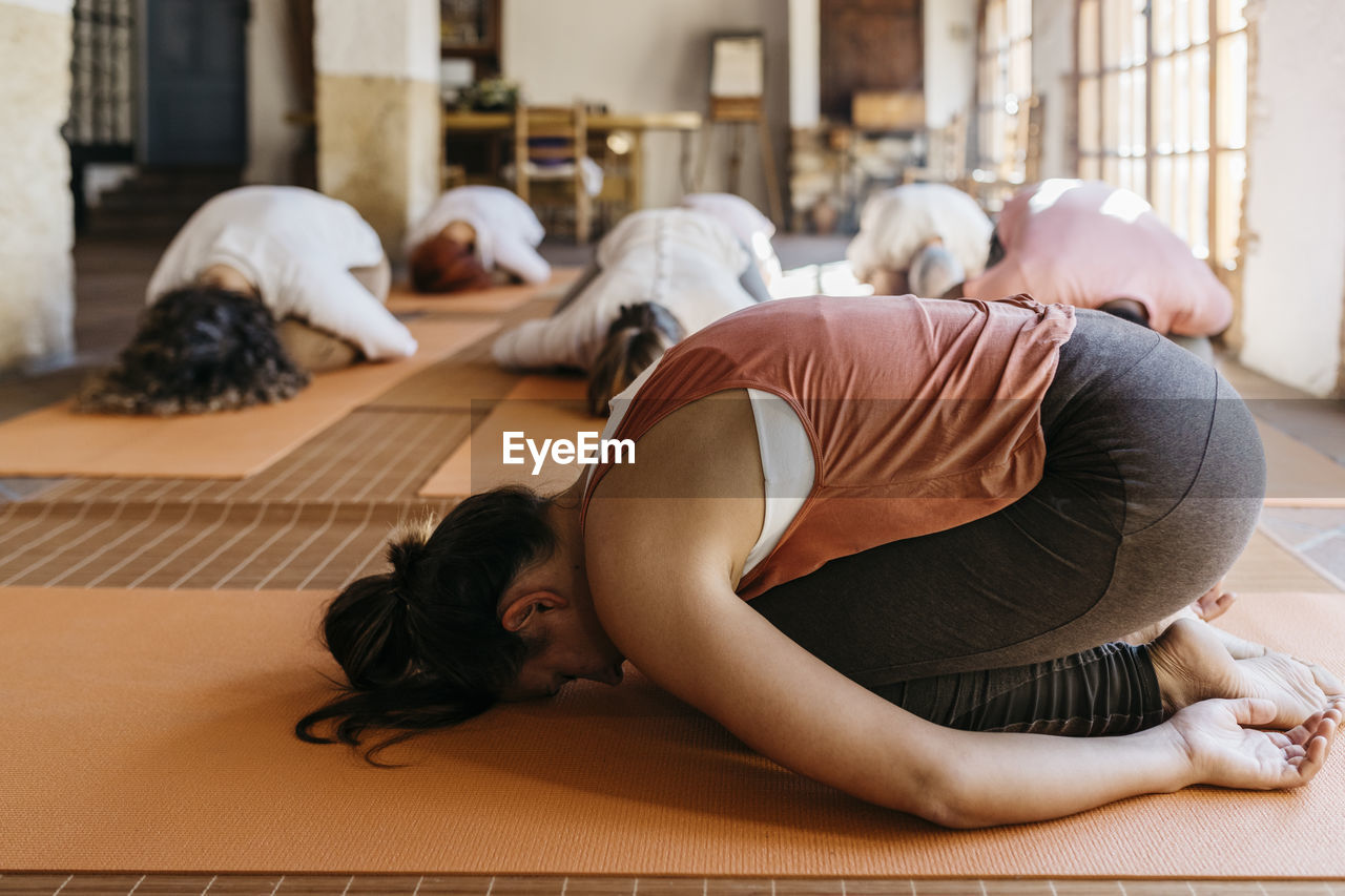 Yoga instructor doing exercise in front of students at class