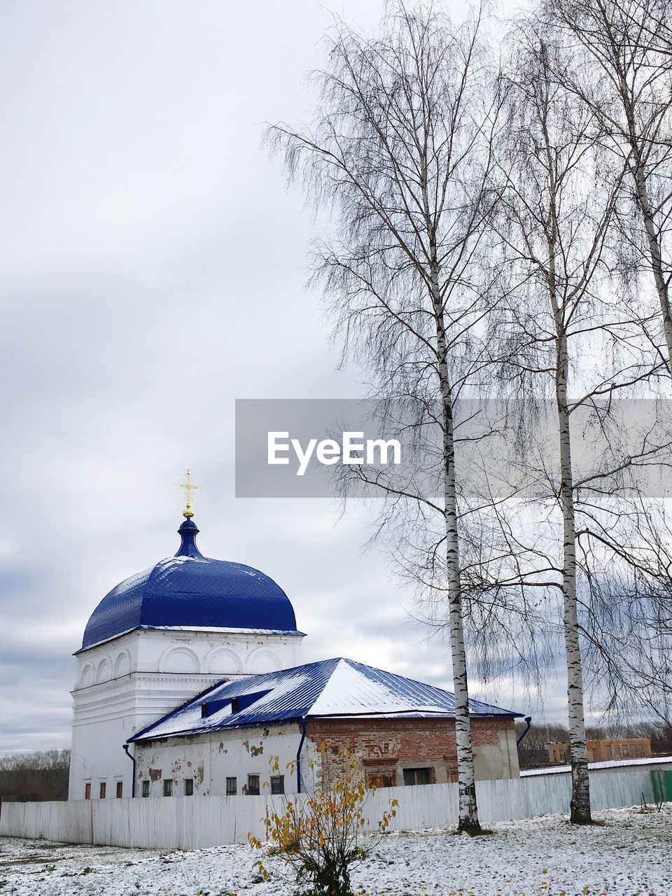 Church by building against sky during winter