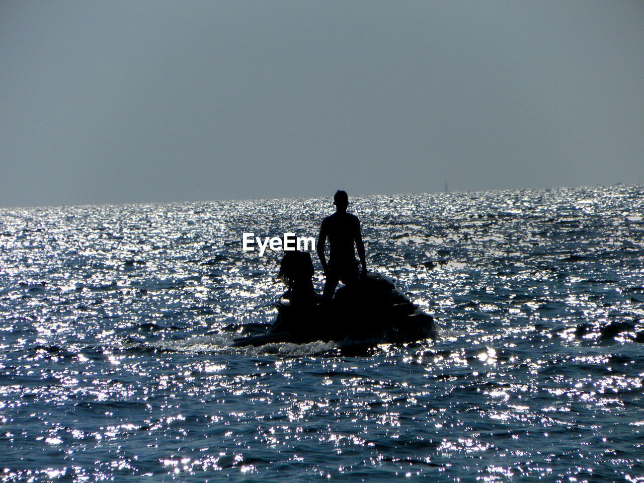 Silhouette people jet skiing at calm sea