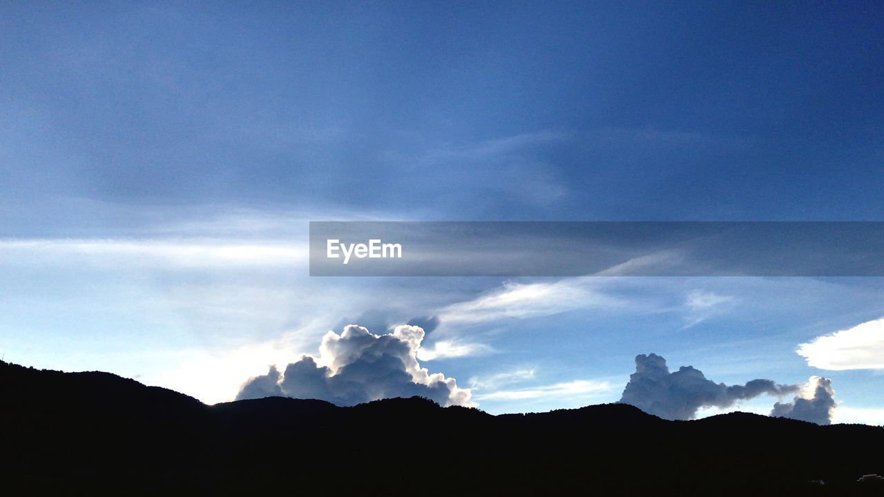 LOW ANGLE VIEW OF SILHOUETTE MOUNTAINS AGAINST BLUE SKY