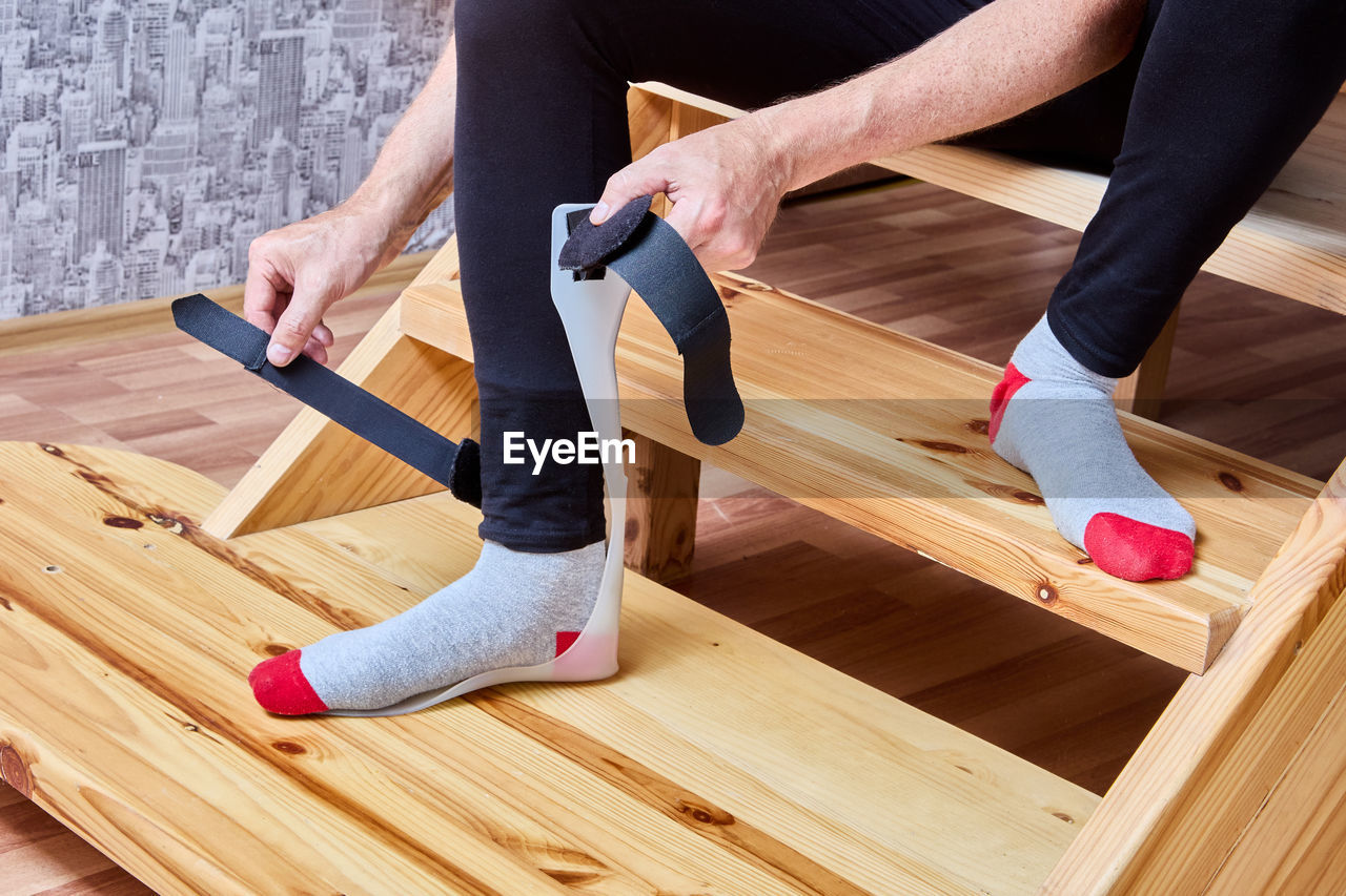 low section of man tying shoelace on wood