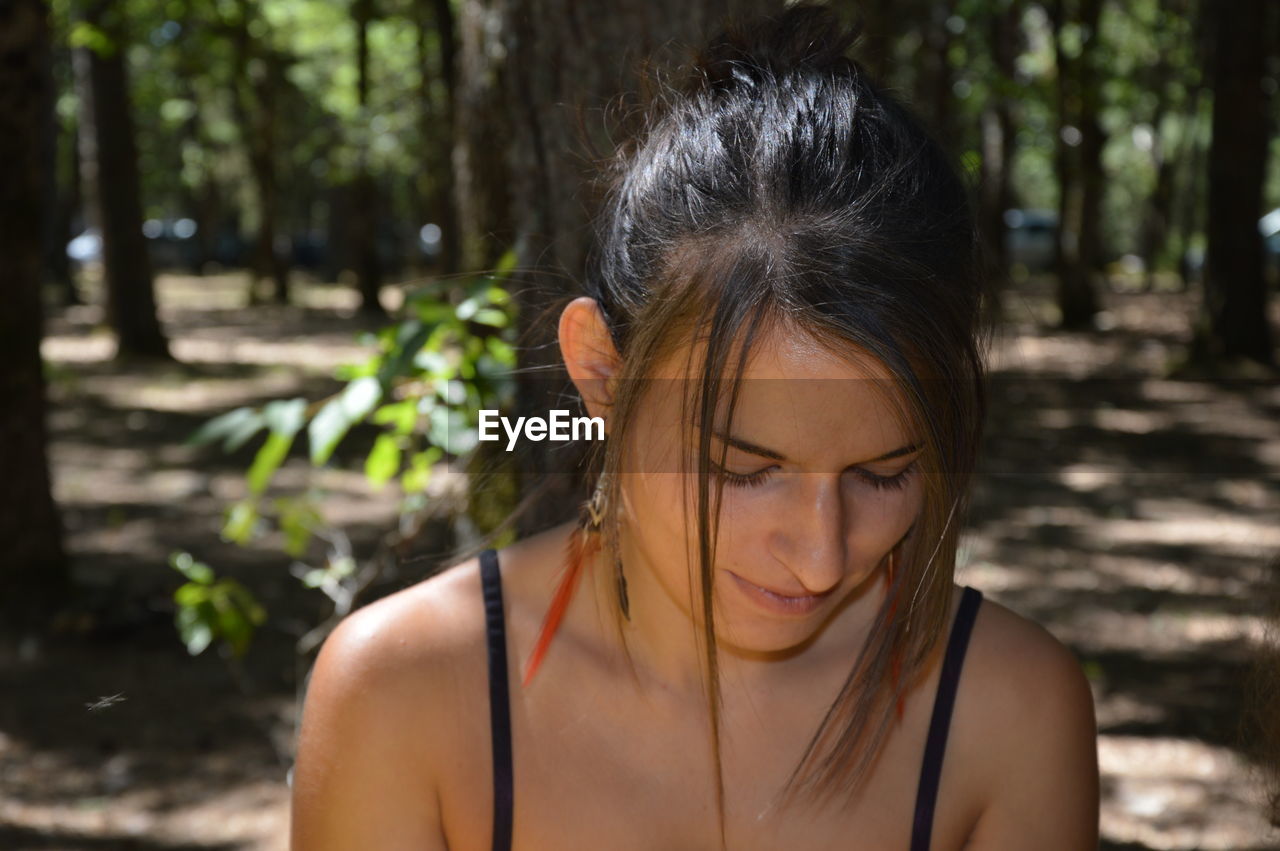 Close-up of beautiful young woman against trees in forest 