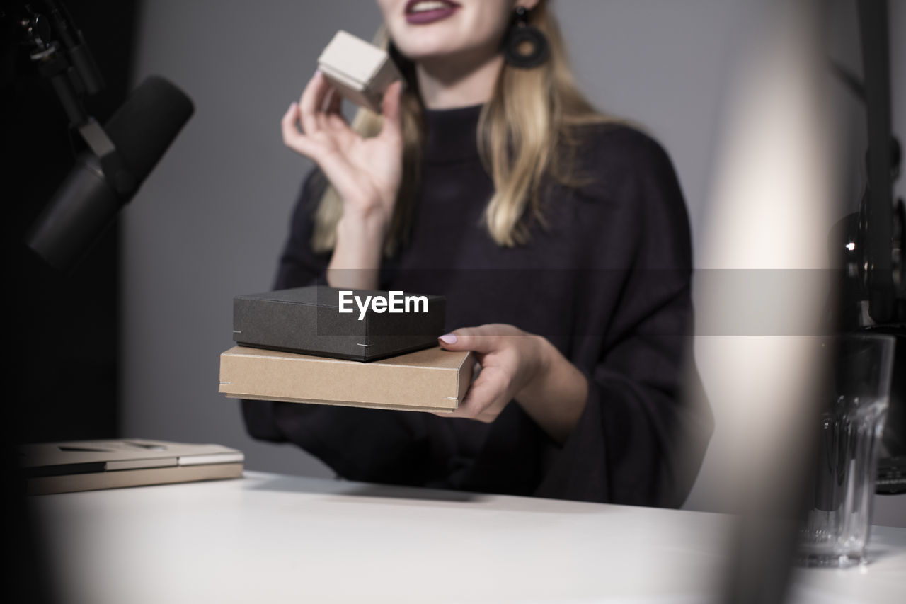 Midsection of businesswoman showing product while recording on camera