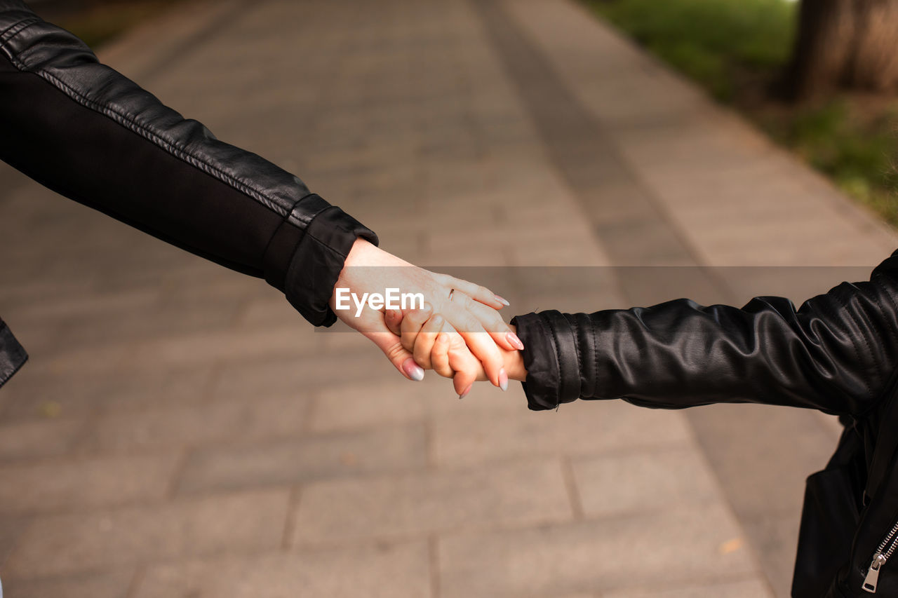 Midsection of man holding hands on footpath