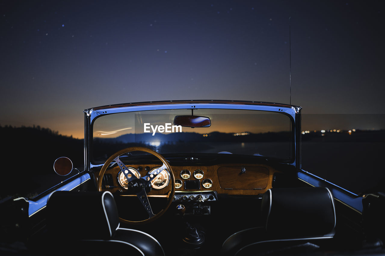 Illuminated vintage car against sky at night