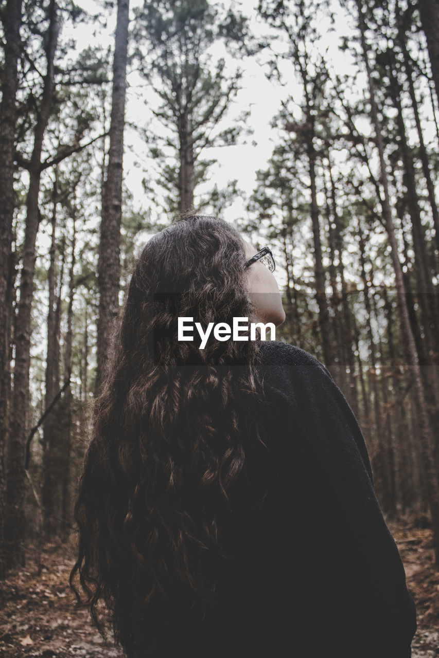 Rear view of young woman standing in forest