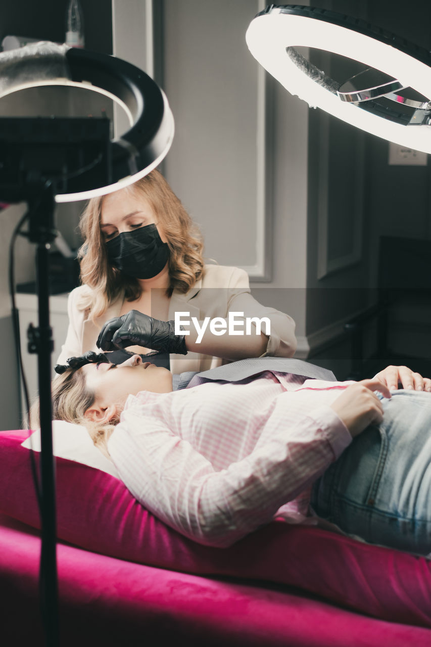 young woman using laptop while lying on bed at home